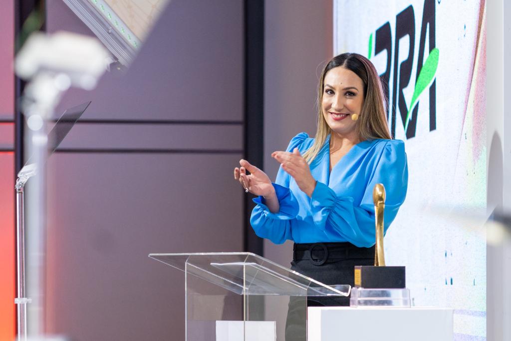 Marusa Trevisan em premiação, aplaudindo no palco